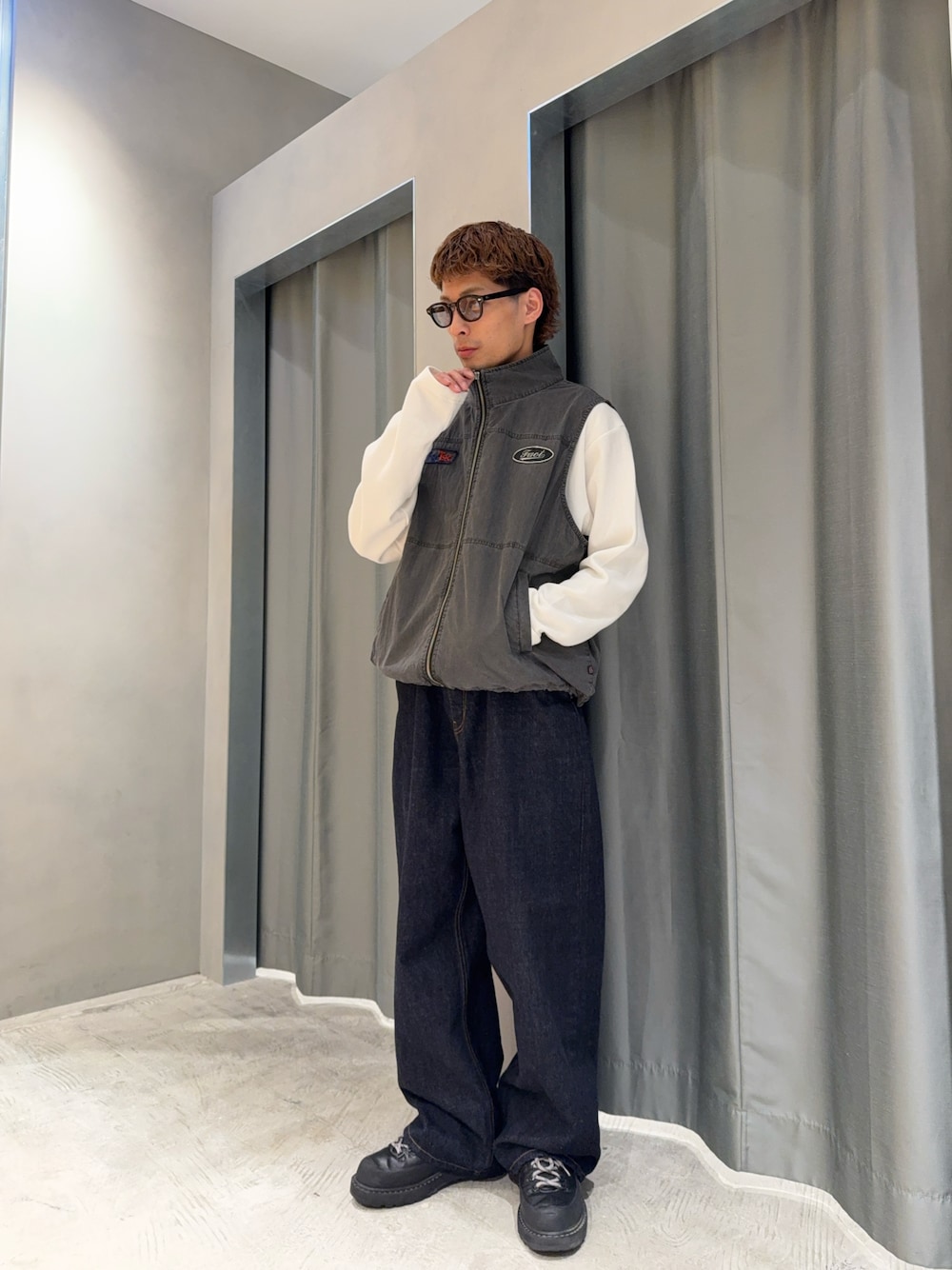 ブルー系のデニムパンツ、ブラック系のブーツ、グレー系のベストを着用したメンズの春コーディネートの1枚目の写真