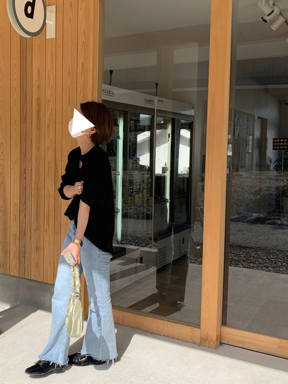 グリーン系のハンドバッグ、ブラック系のシャツ/ブラウス、ブルー系のデニムパンツを着用したレディースの秋コーディネートの1枚目の写真