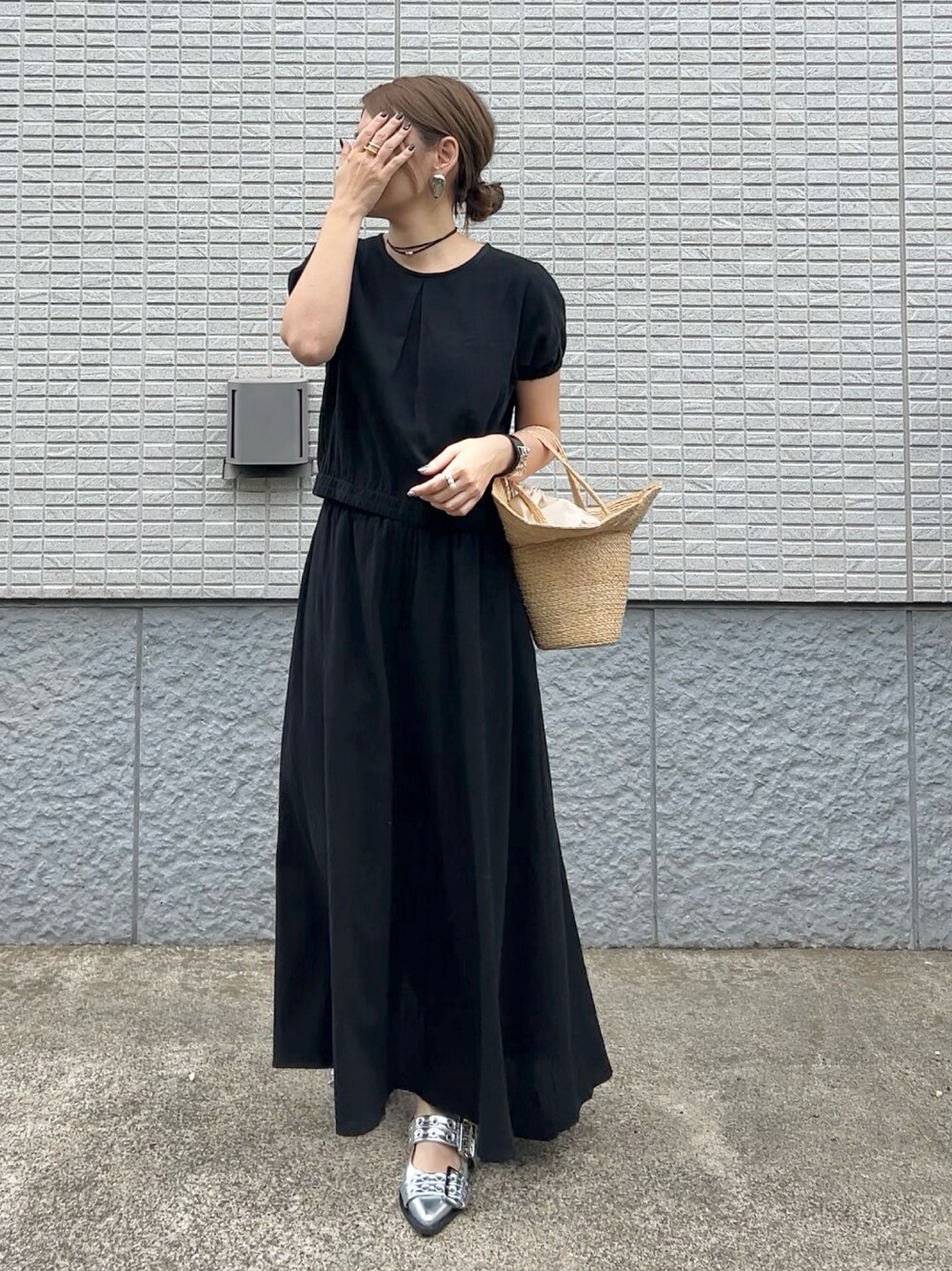 ブラック系のセットアップ、ベージュ系のかごバッグ、シルバー系のパンプスを着用したレディースの春コーディネートの1枚目の写真