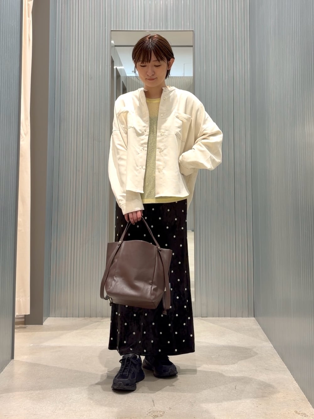 イエロー系のTシャツ/カットソー、ホワイト系のシャツ/ブラウス、ブラック系のスカートを着用したレディースの秋コーディネートの1枚目の写真