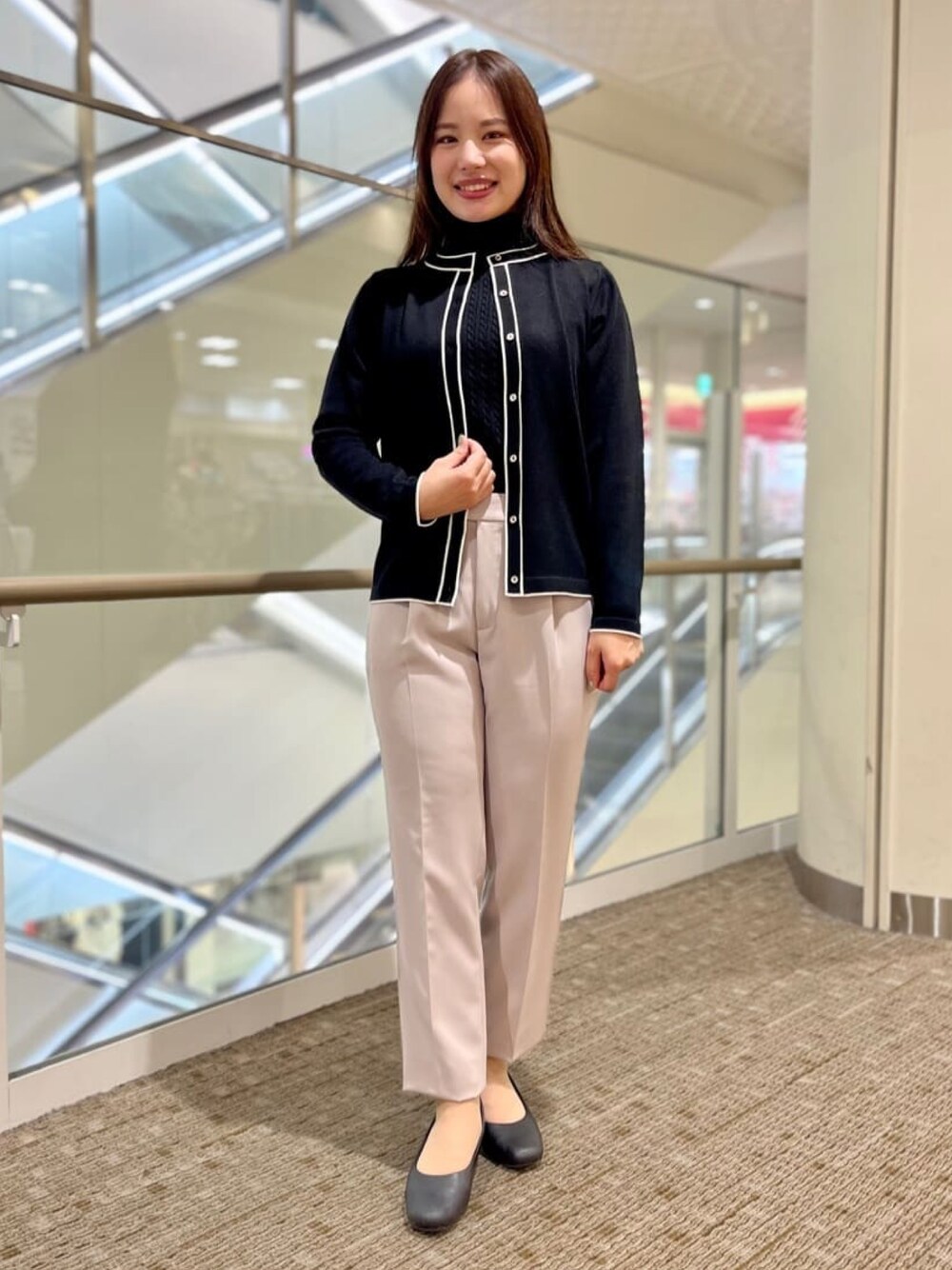 ブラック系のニット/セーター、ブラック系のカーディガン/ボレロ、ベージュ系のスーツパンツを着用したレディースの冬コーディネートの1枚目の写真