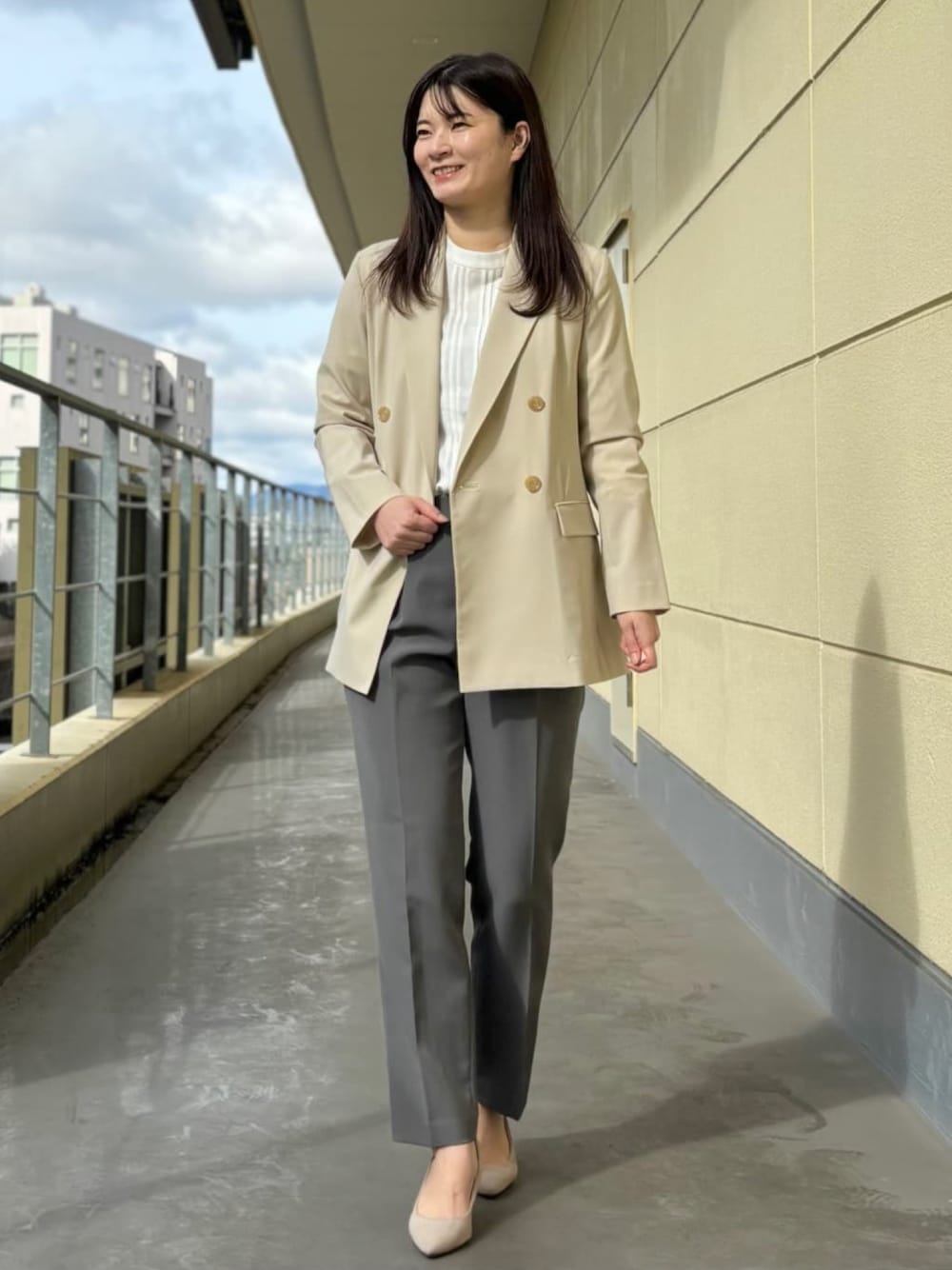 ベージュ系のスーツジャケット、ホワイト系のシャツ/ブラウス、グレー系のスーツパンツを着用したレディースの春コーディネートの1枚目の写真