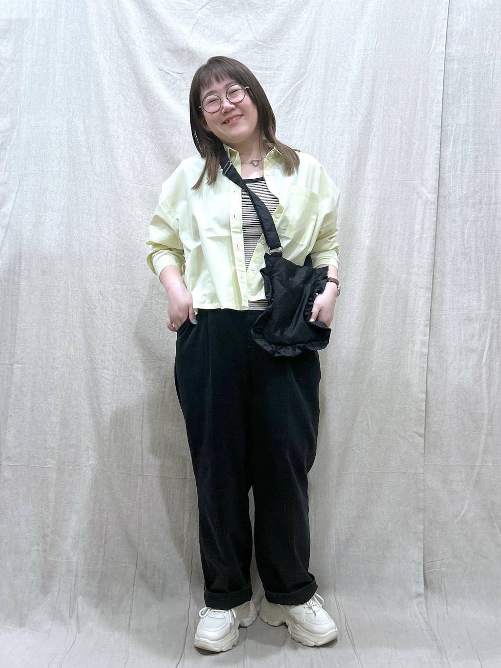 ブラック系のタンクトップ、ブラック系のデニムパンツ、イエロー系のシャツ/ブラウスを着用したレディースの春コーディネートの1枚目の写真