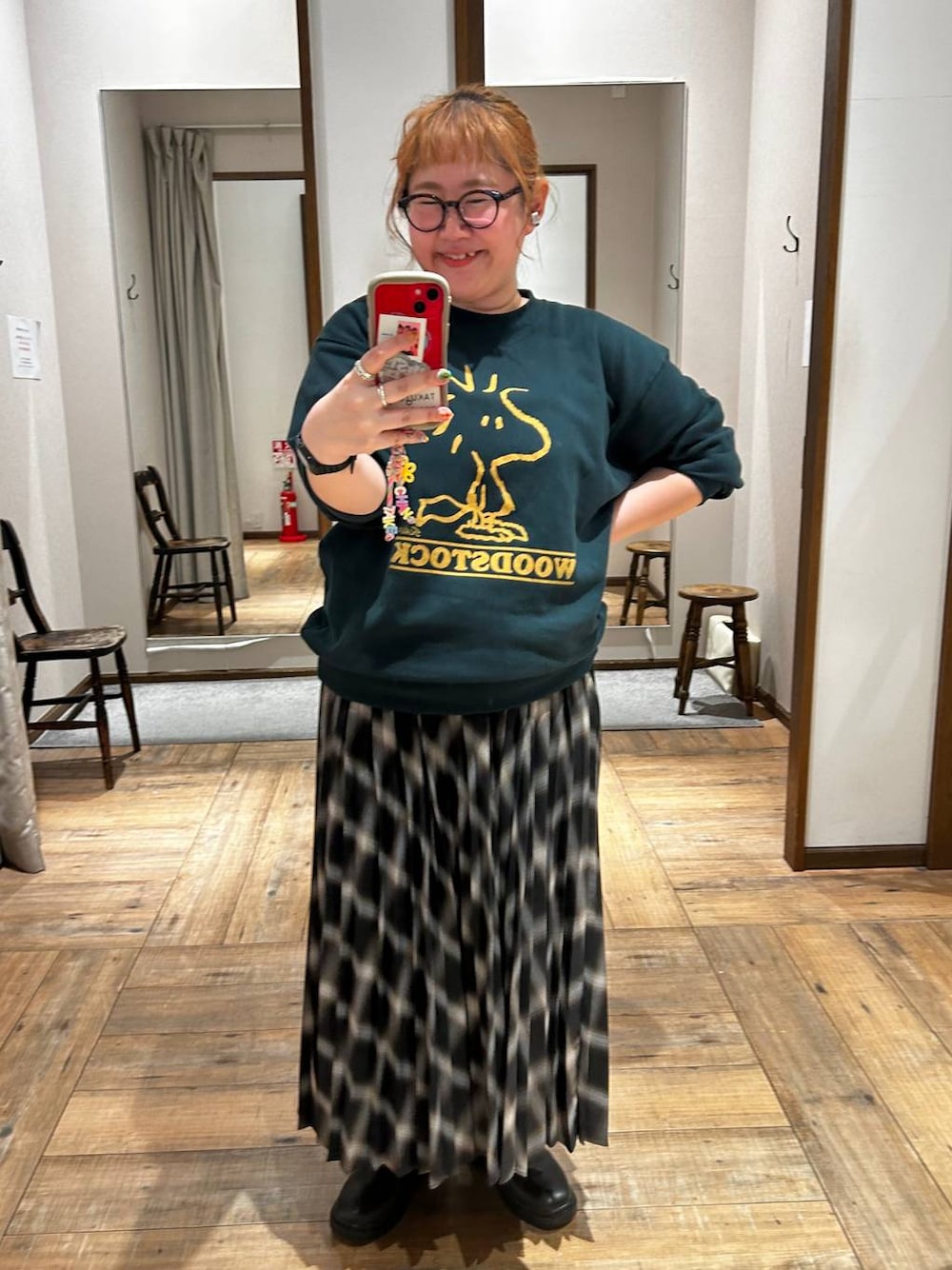 ブラック系のブーツ、グリーン系のスウェット、ブラック系のスカートを着用したレディースの秋コーディネートの1枚目の写真