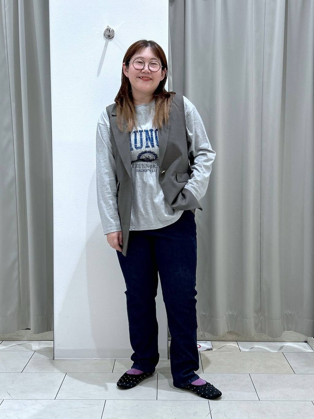 ブルー系のデニムパンツ、ブラック系のバレエシューズ、ブラウン系のベストを着用したレディースの秋コーディネートの1枚目の写真