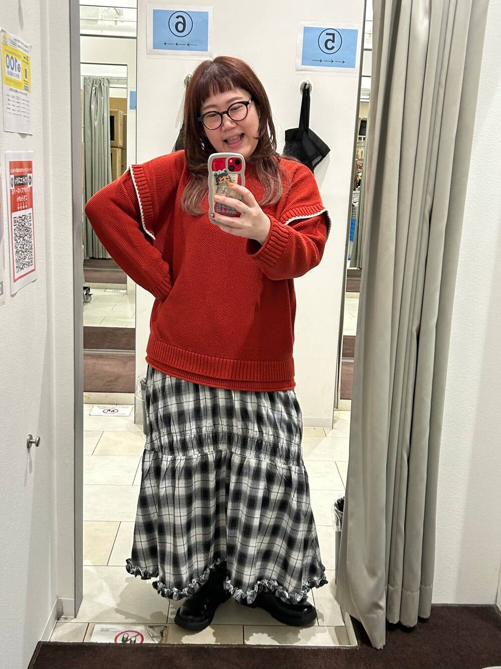 レッド系のニット/セーター、ブラック系のスカート、ブラック系のブーツを着用したレディースの秋コーディネートの1枚目の写真