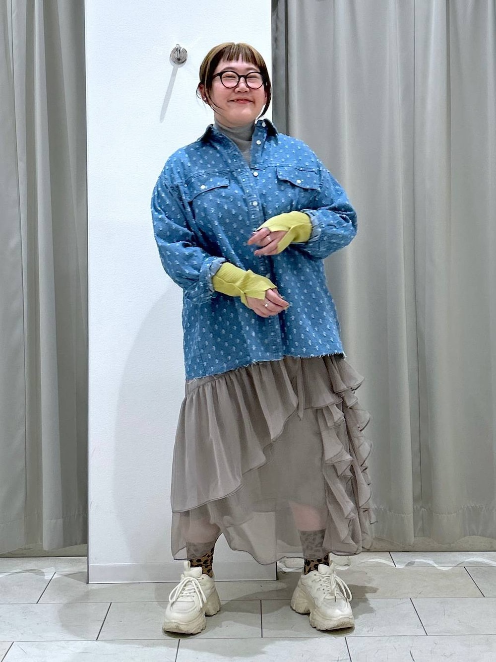 グレー系のニット/セーター、グレー系のスカート、ホワイト系のスニーカーを着用したレディースの冬コーディネートの1枚目の写真