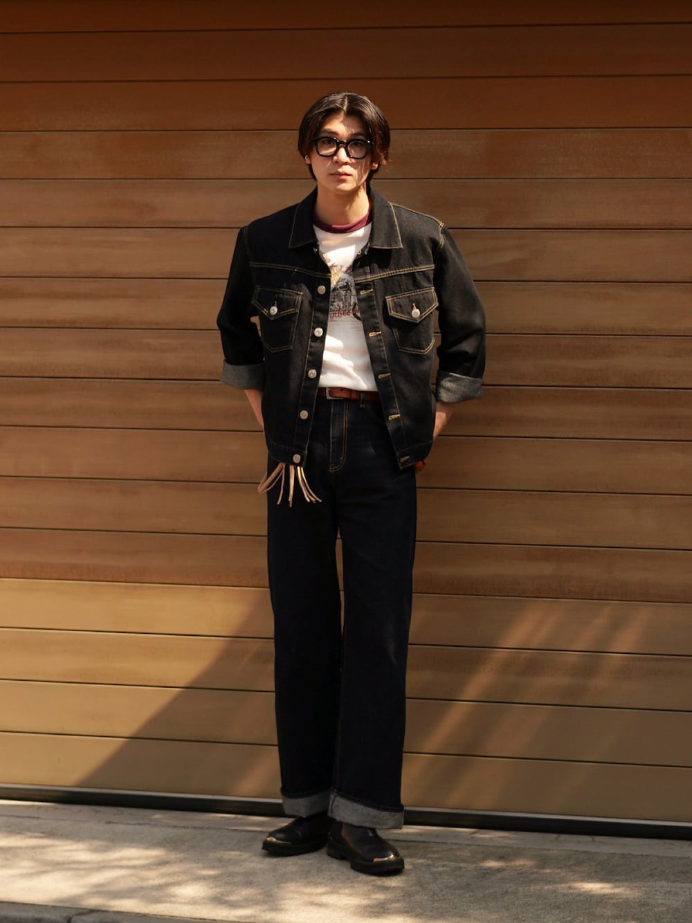 ブルー系のデニムパンツ、ブラック系のブーツ、レッド系のTシャツ/カットソーを着用したメンズの春コーディネートの1枚目の写真