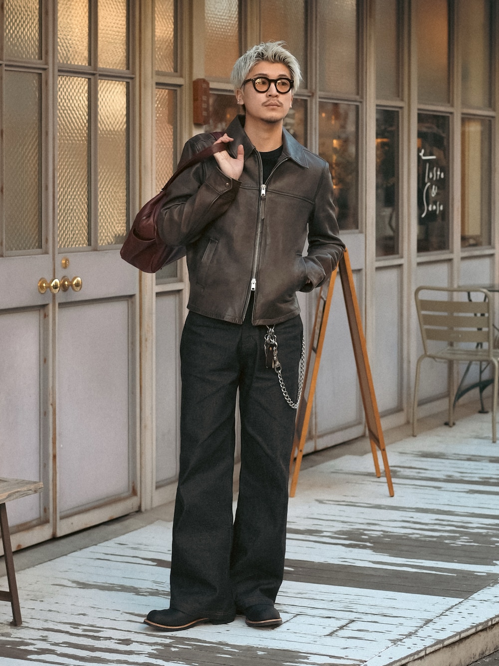 ブラック系のデニムパンツ、レッド系のボストンバッグ、ブラック系のブーツを着用したメンズの冬コーディネートの1枚目の写真