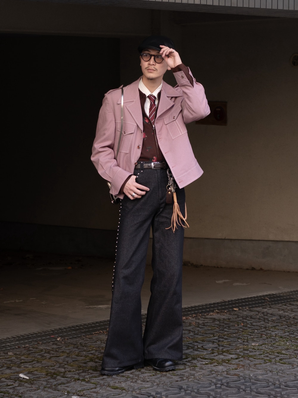 ブラック系のデニムパンツ、ピンク系のミリタリージャケット、ブラウン系のニット/セーターを着用したメンズの春コーディネートの1枚目の写真