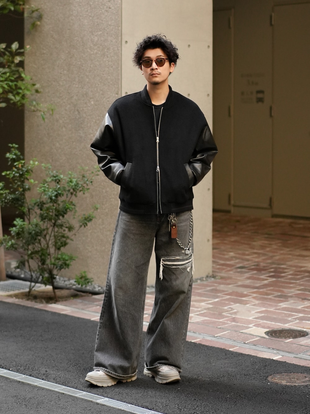 ブラック系のスタジャン、ブラック系のデニムパンツ、グレー系のスニーカーを着用したメンズの秋コーディネートの1枚目の写真