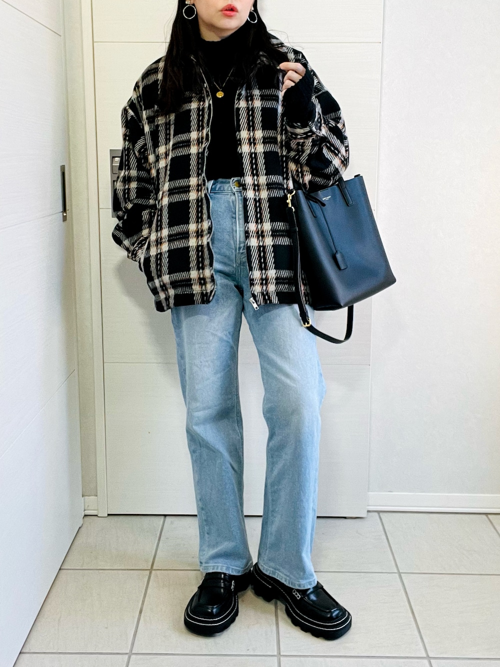ブラック系のブルゾン、ブラック系のニット/セーター、ブルー系のデニムパンツを着用したレディースの冬コーディネートの1枚目の写真