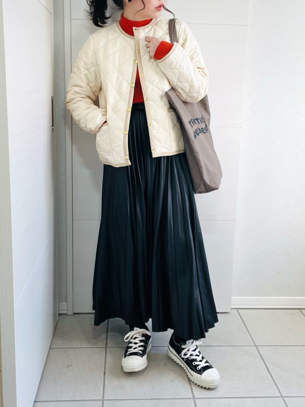 ホワイト系のノーカラージャケット、オレンジ系のニット/セーター、ブラック系のスカートを着用したレディースの秋コーディネートの1枚目の写真