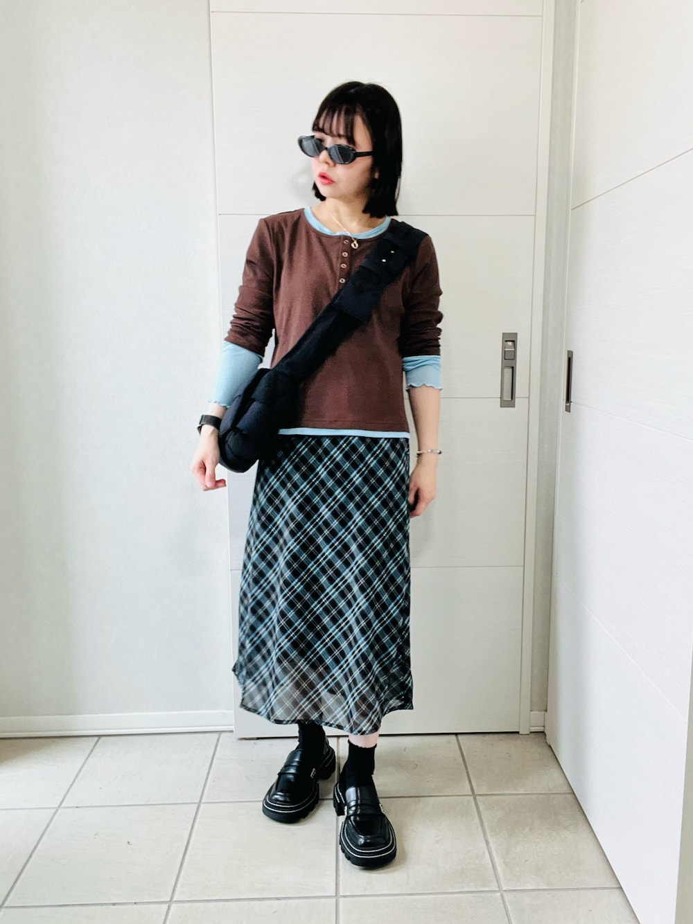 ブラウン系のTシャツ/カットソー、ブラウン系のスカート、ブラック系のローファーを着用したレディースの秋コーディネートの1枚目の写真
