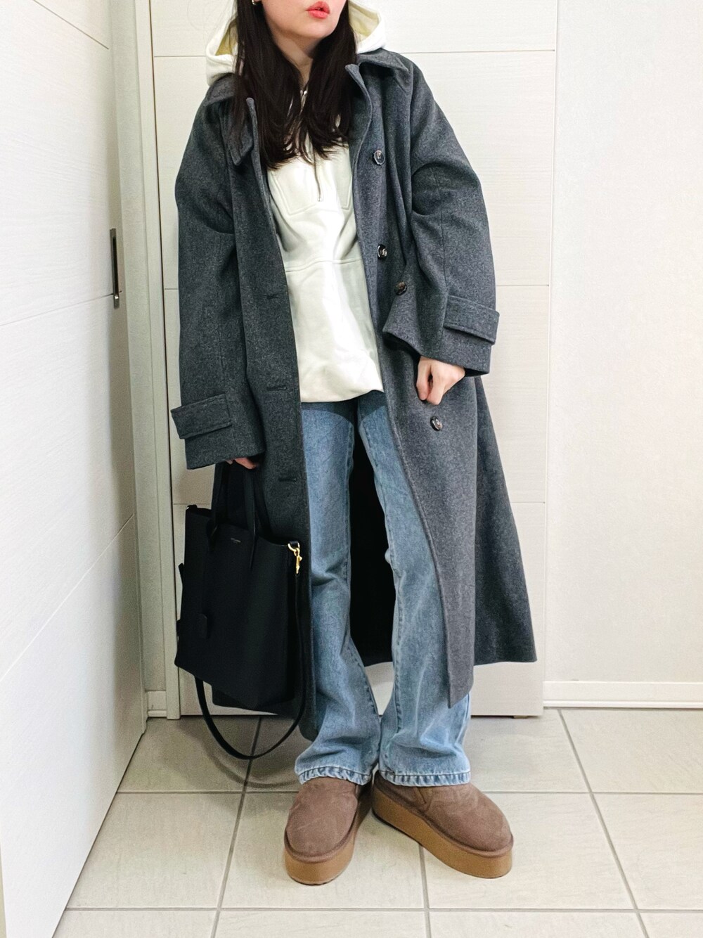 ホワイト系のパーカー、グレー系のステンカラーコート、ブルー系のデニムパンツを着用したレディースの冬コーディネートの1枚目の写真
