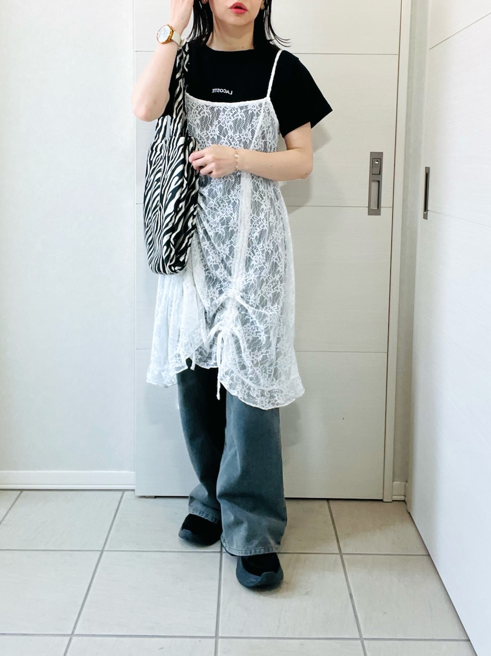 ホワイト系のチュニック、ブラック系のTシャツ/カットソー、ブルー系のデニムパンツを着用したレディースの春コーディネートの1枚目の写真