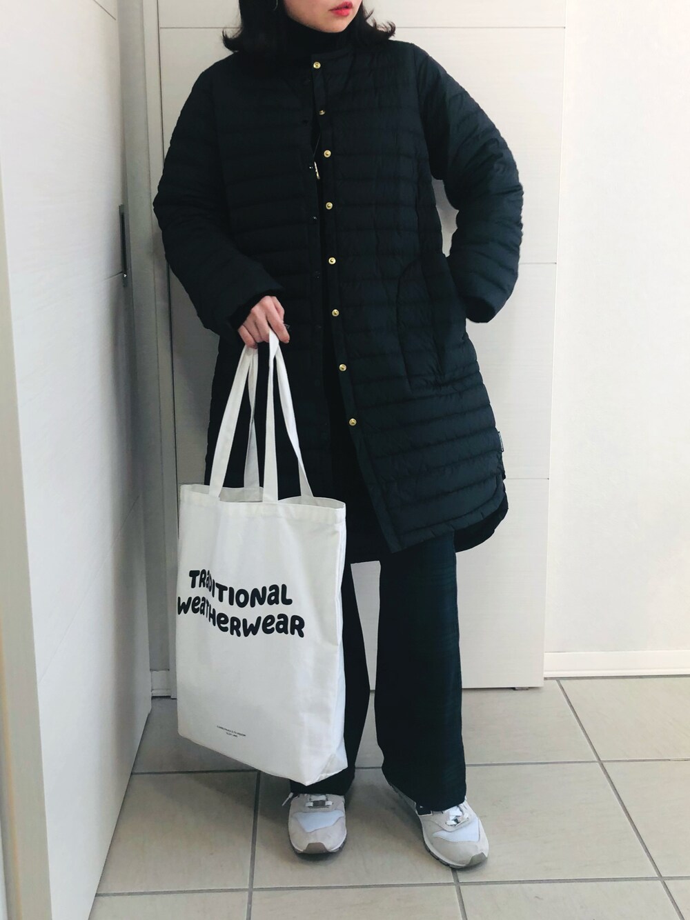 ブラック系のダウンジャケット/コート、ブラック系のニット/セーター、グリーン系のスラックスを着用したレディースの冬コーディネートの1枚目の写真