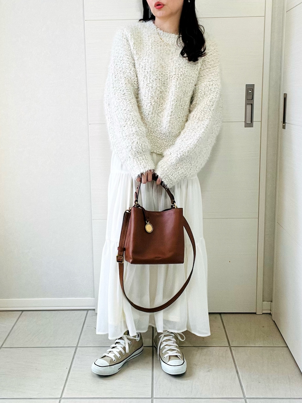 ブラウン系のショルダーバッグ、ベージュ系のニット/セーター、ホワイト系のスカートを着用したレディースの秋コーディネートの1枚目の写真
