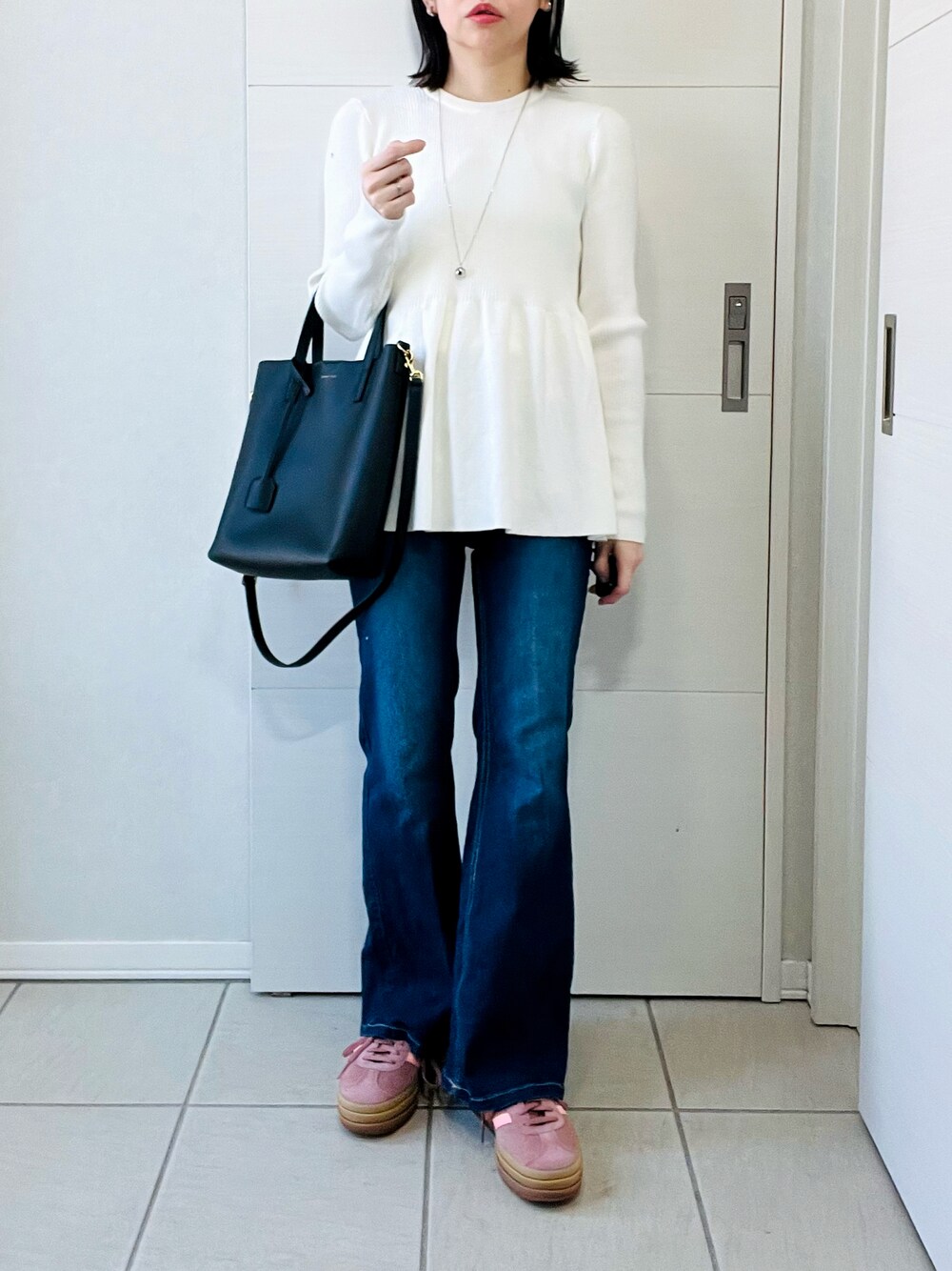 ホワイト系のニット/セーター、ブルー系のデニムパンツ、レッド系のスニーカーを着用したレディースの春コーディネートの1枚目の写真