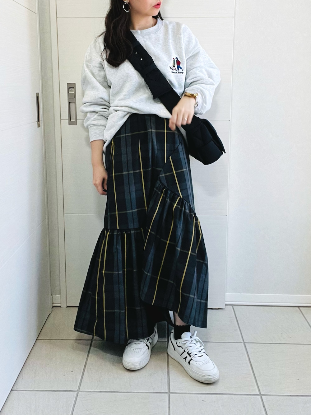 グレー系のスウェット、ブラック系のスカート、ホワイト系のスニーカーを着用したレディースの秋コーディネートの1枚目の写真