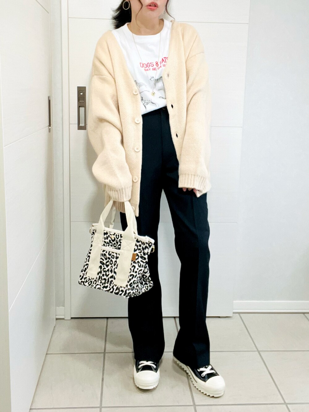 ホワイト系のカーディガン/ボレロ、ホワイト系のTシャツ/カットソー、ブラック系のスラックスを着用したレディースの秋コーディネートの1枚目の写真