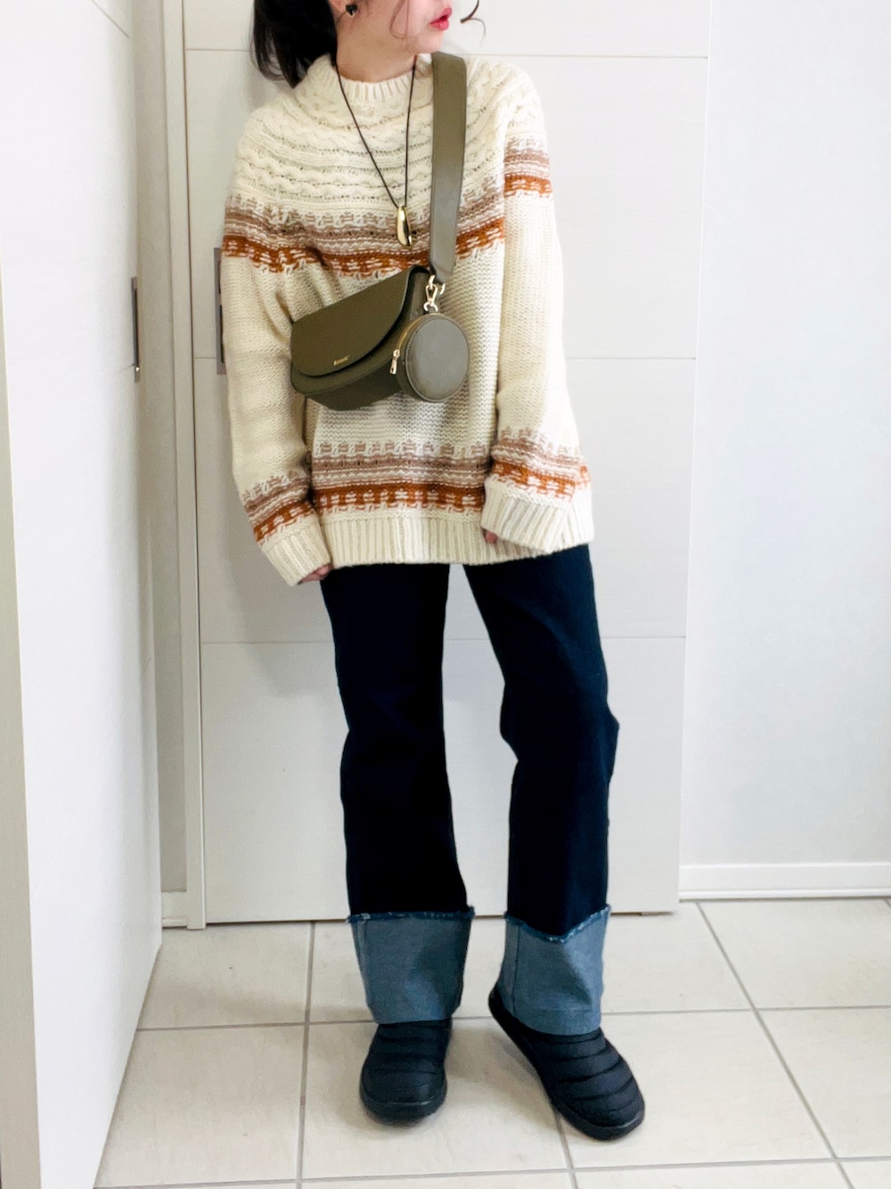 ブラウン系のニット/セーター、ブラウン系のその他アウター、ブルー系のデニムパンツを着用したレディースの冬コーディネートの1枚目の写真