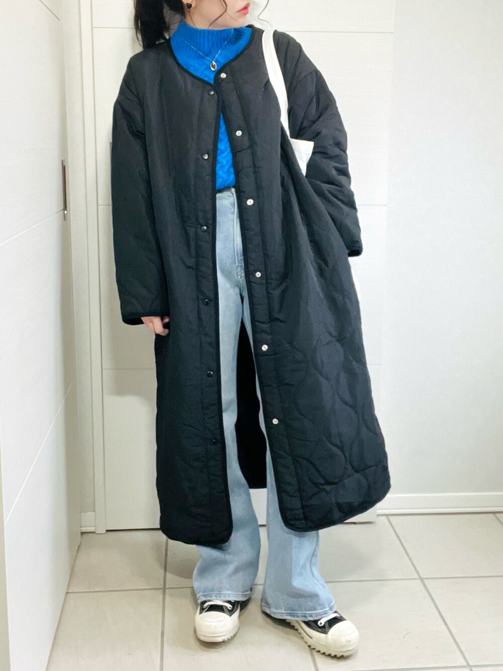 ブラック系のノーカラーコート、ブルー系のニット/セーター、ブルー系のデニムパンツを着用したレディースの秋コーディネートの1枚目の写真