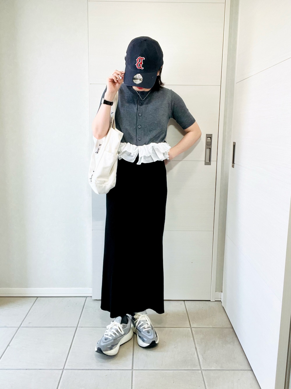 グレー系のカーディガン/ボレロ、ブラック系のスカート、グレー系のスニーカーを着用したレディースの春コーディネートの1枚目の写真