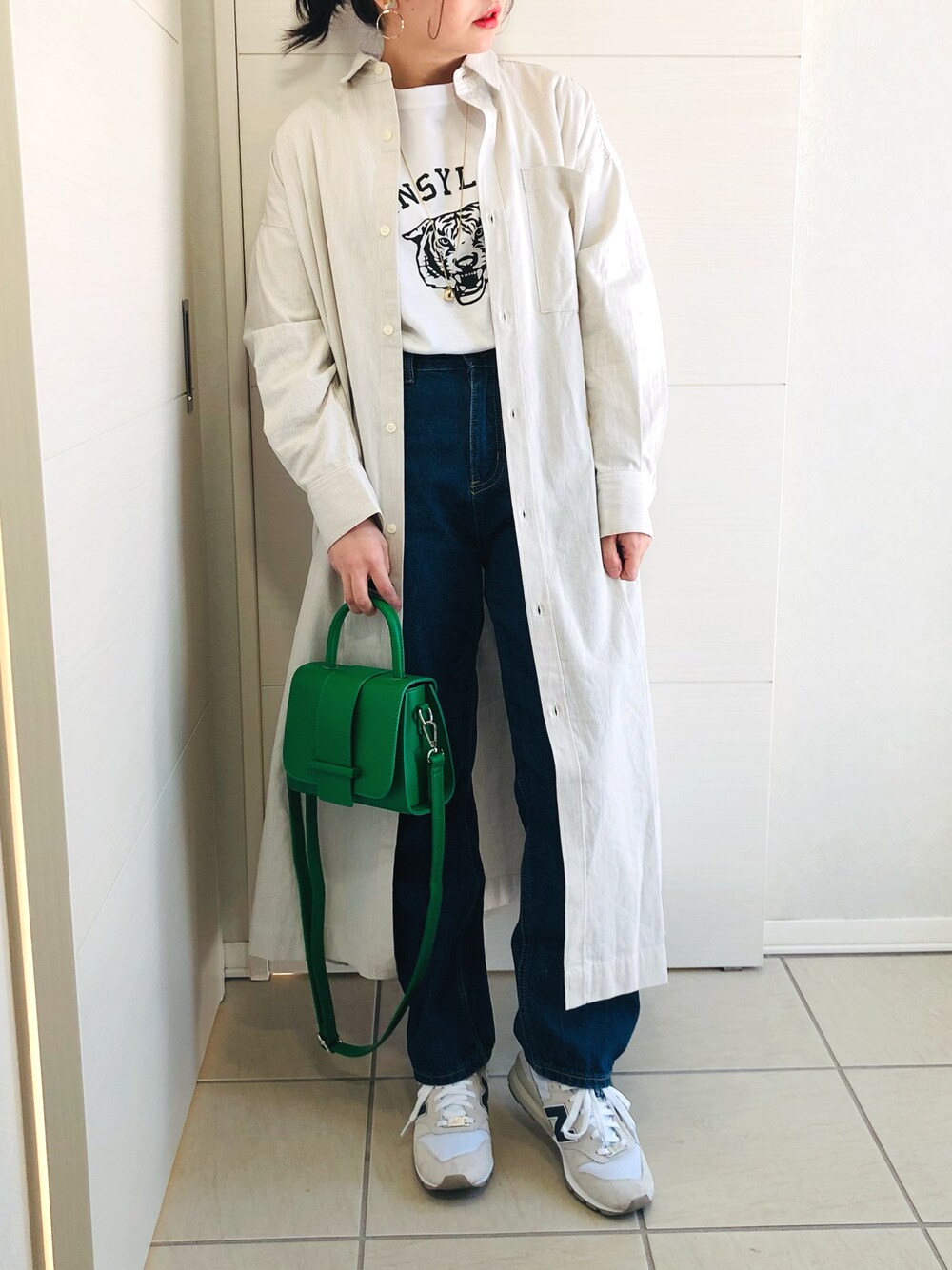 ベージュ系のワンピース、ホワイト系のTシャツ/カットソー、ブルー系のデニムパンツを着用したレディースの冬コーディネートの1枚目の写真