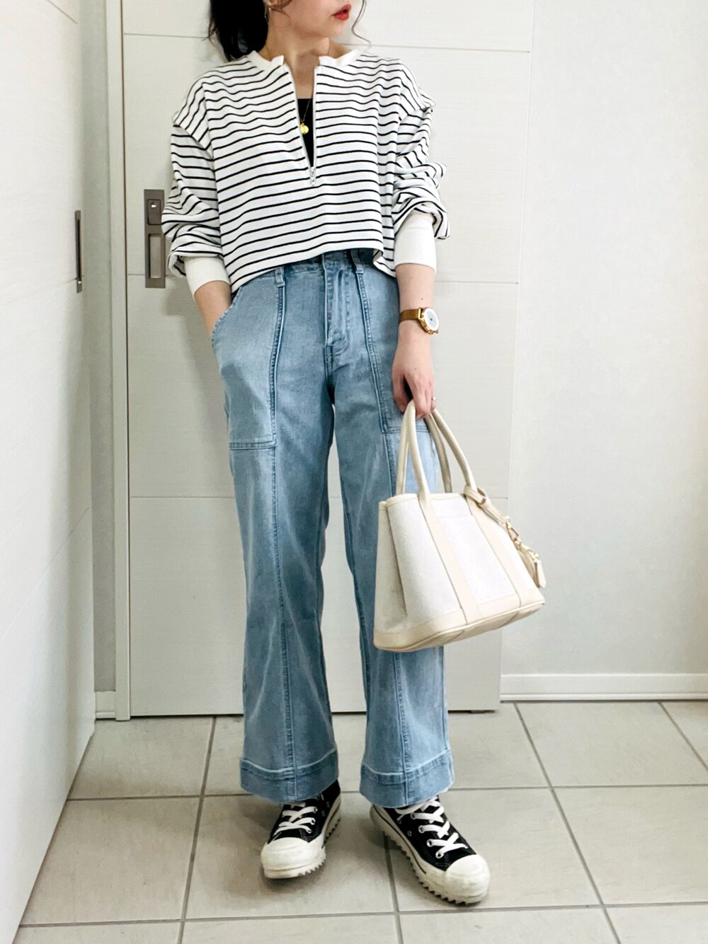 ブラック系のワンピース、ブルー系のデニムパンツ、ブラック系のスニーカーを着用したレディースの春コーディネートの1枚目の写真