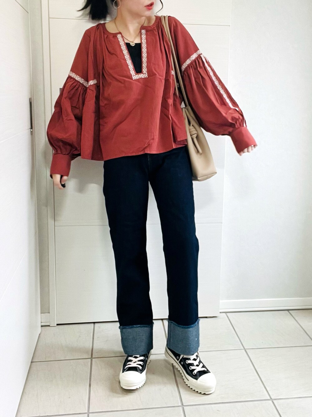 ブラウン系のシャツ/ブラウス、ブルー系のデニムパンツ、ブラック系のスニーカーを着用したレディースの秋コーディネートの1枚目の写真