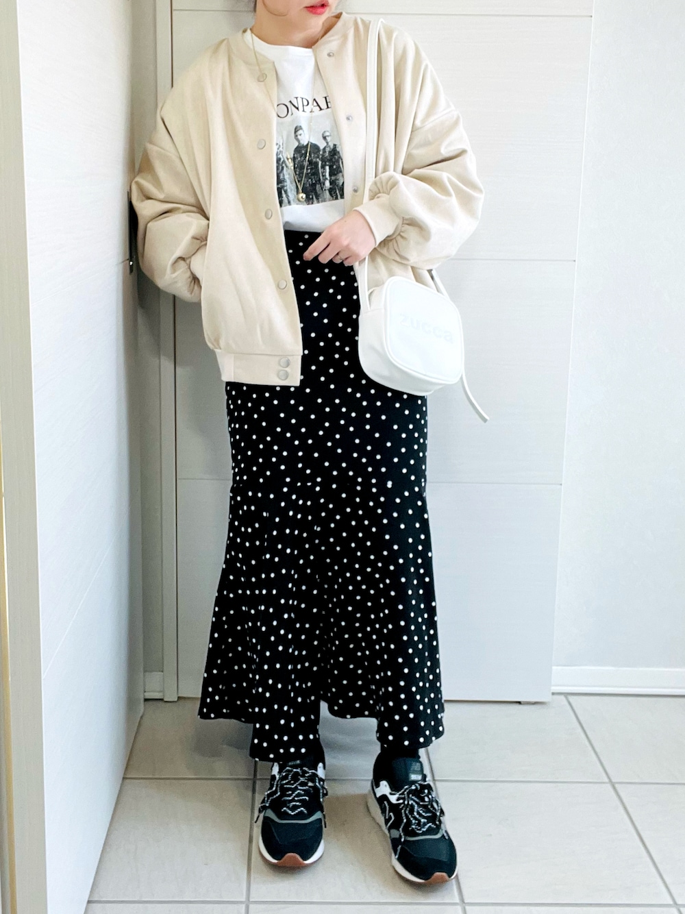 ホワイト系のスタジャン、ホワイト系のTシャツ/カットソー、ブラック系のスカートを着用したレディースの春コーディネートの1枚目の写真