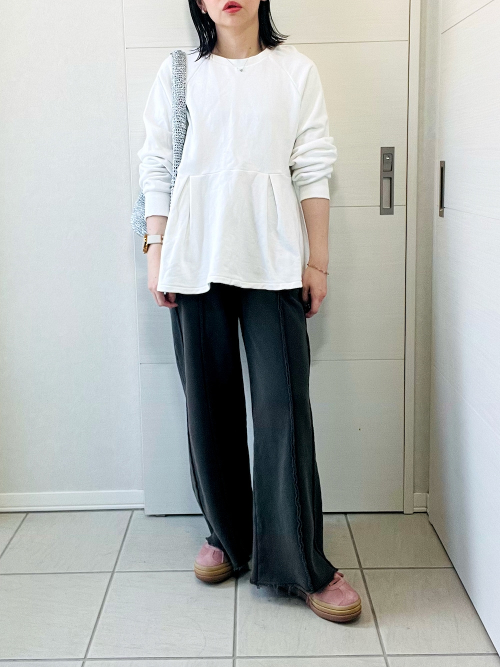 ホワイト系のスウェット、ブラック系のスウェットパンツ、レッド系のスニーカーを着用したレディースの春コーディネートの1枚目の写真