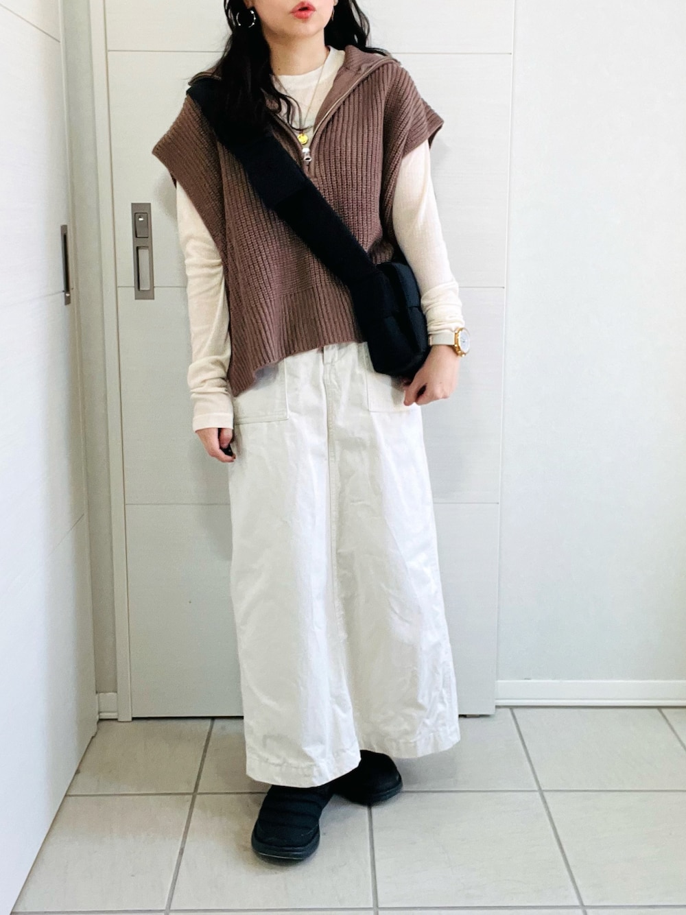 ブラウン系のベスト、ホワイト系のTシャツ/カットソー、ホワイト系のスカートを着用したレディースの秋コーディネートの1枚目の写真
