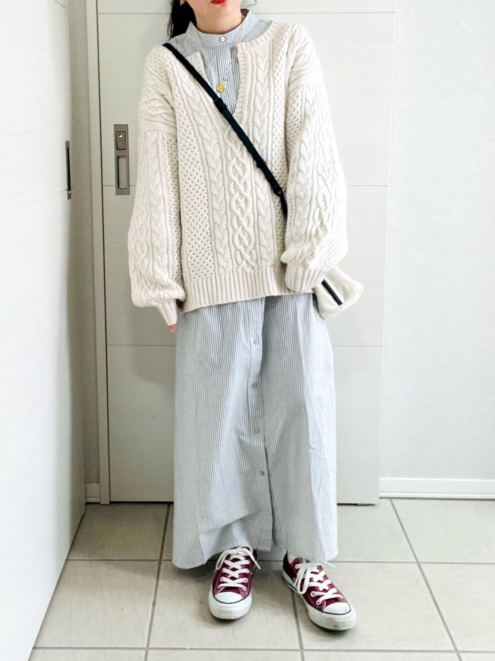ブラック系のワンピース、ホワイト系のニット/セーター、レッド系のスニーカーを着用したレディースの冬コーディネートの1枚目の写真