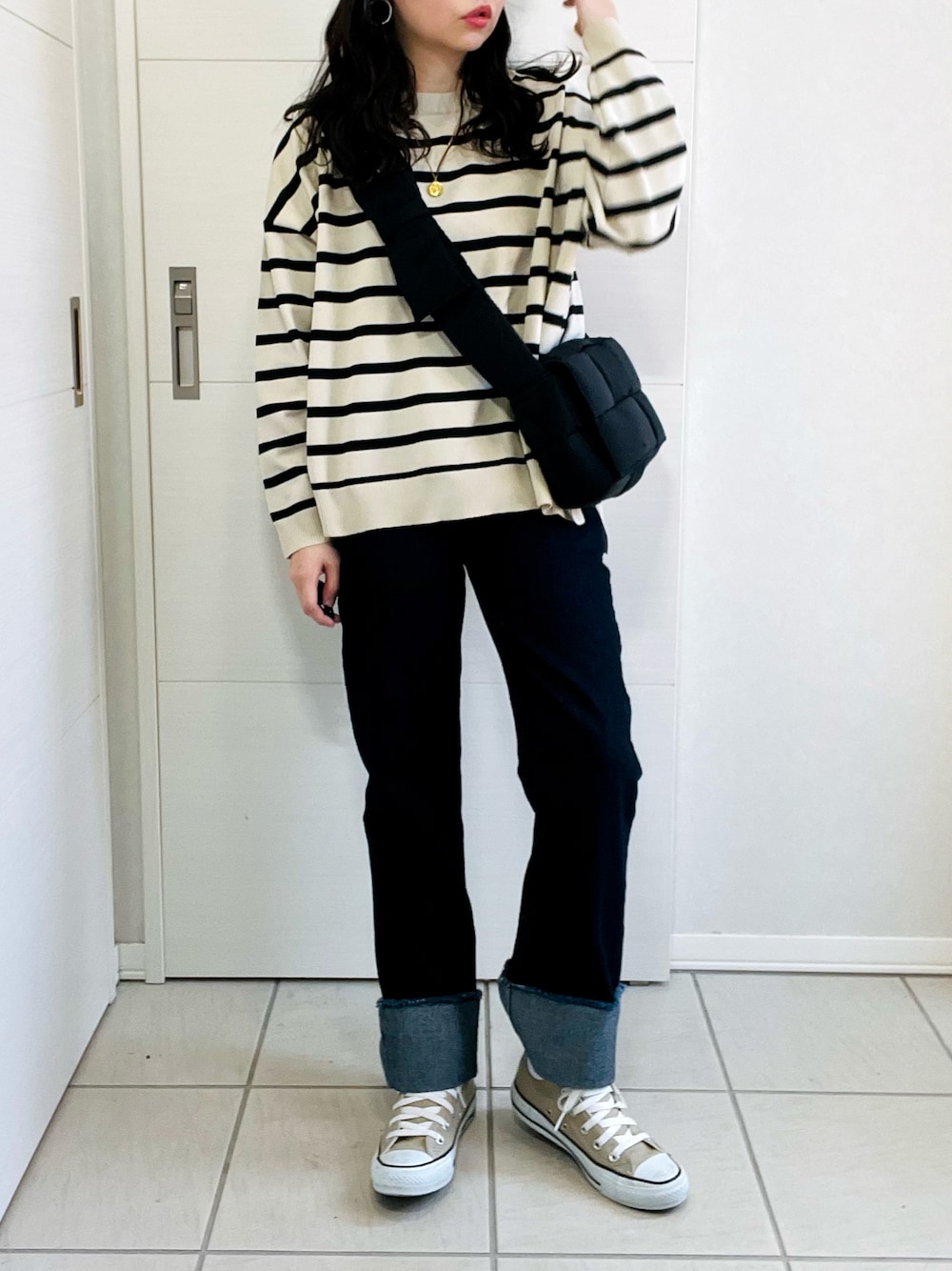 ホワイト系のニット/セーター、ブルー系のデニムパンツ、ベージュ系のスニーカーを着用したレディースの秋コーディネートの1枚目の写真