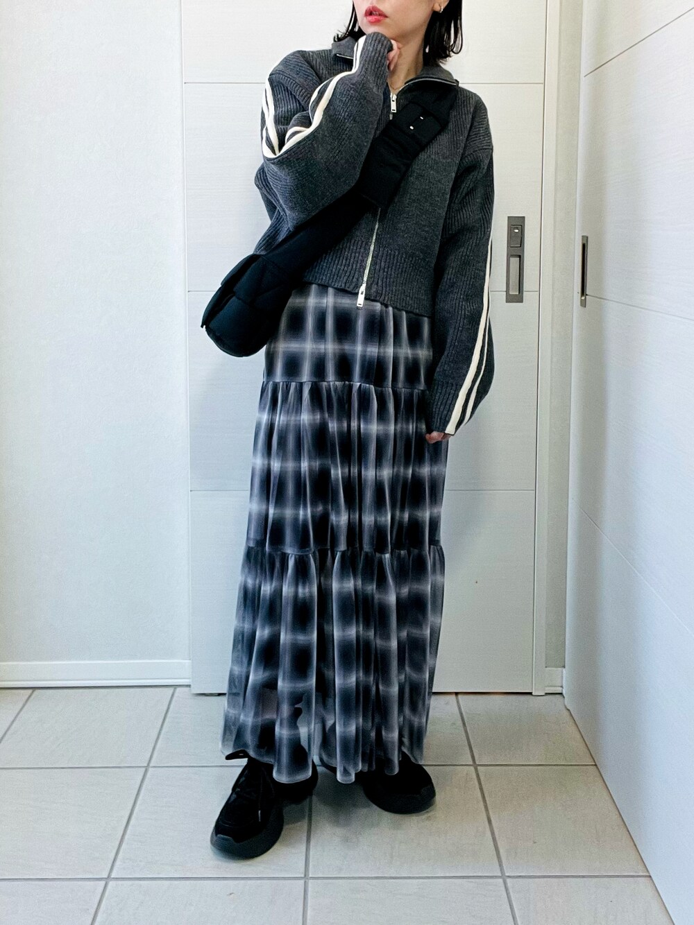 グレー系のニット/セーター、ブラック系のスカート、ブラック系のスニーカーを着用したレディースの冬コーディネートの1枚目の写真