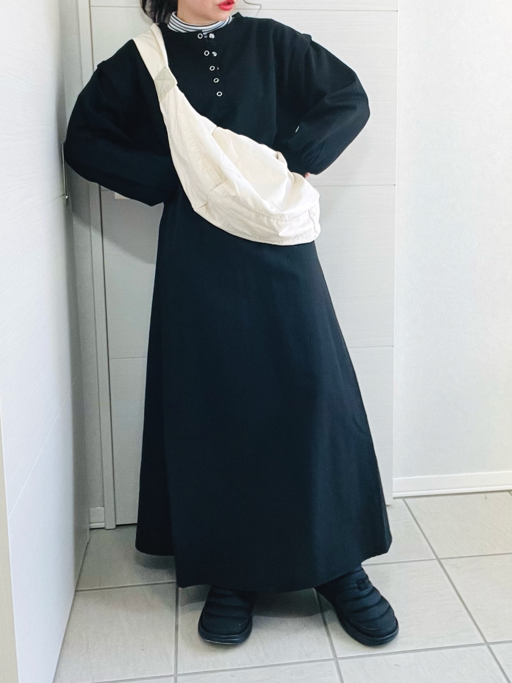 ブラック系のワンピース、ホワイト系のショルダーバッグ、グリーン系のノーカラージャケットを着用したレディースの冬コーディネートの1枚目の写真