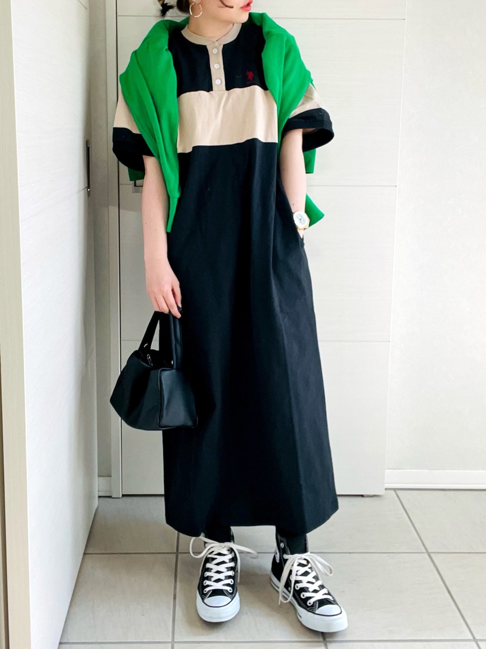 ブラック系のワンピース、グリーン系のカーディガン/ボレロ、ブラック系のスニーカーを着用したレディースの春コーディネートの1枚目の写真
