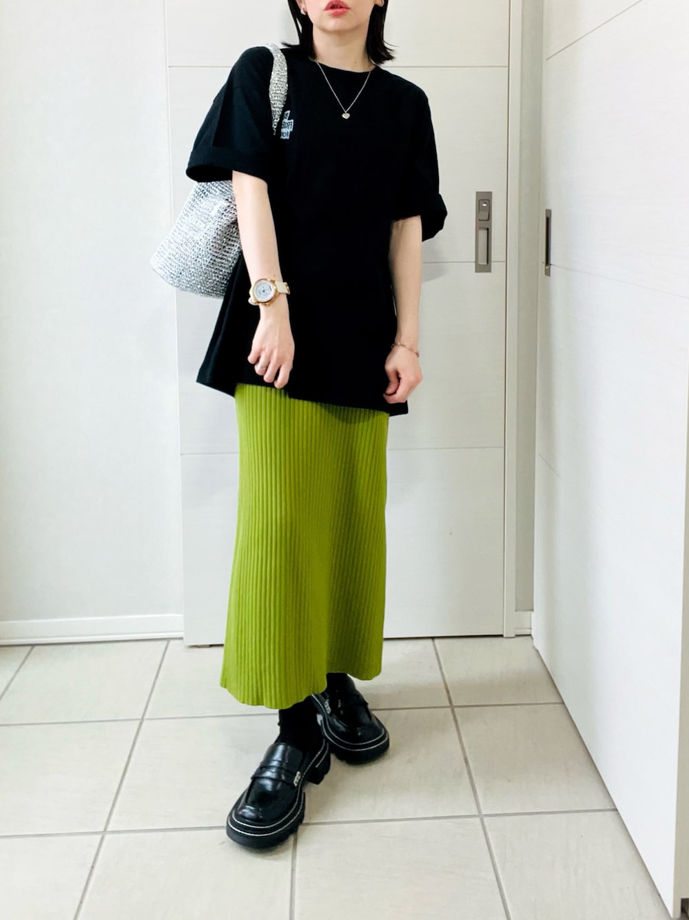 ブラック系のTシャツ/カットソー、グリーン系のスカート、ブラック系のローファーを着用したレディースの春コーディネートの1枚目の写真