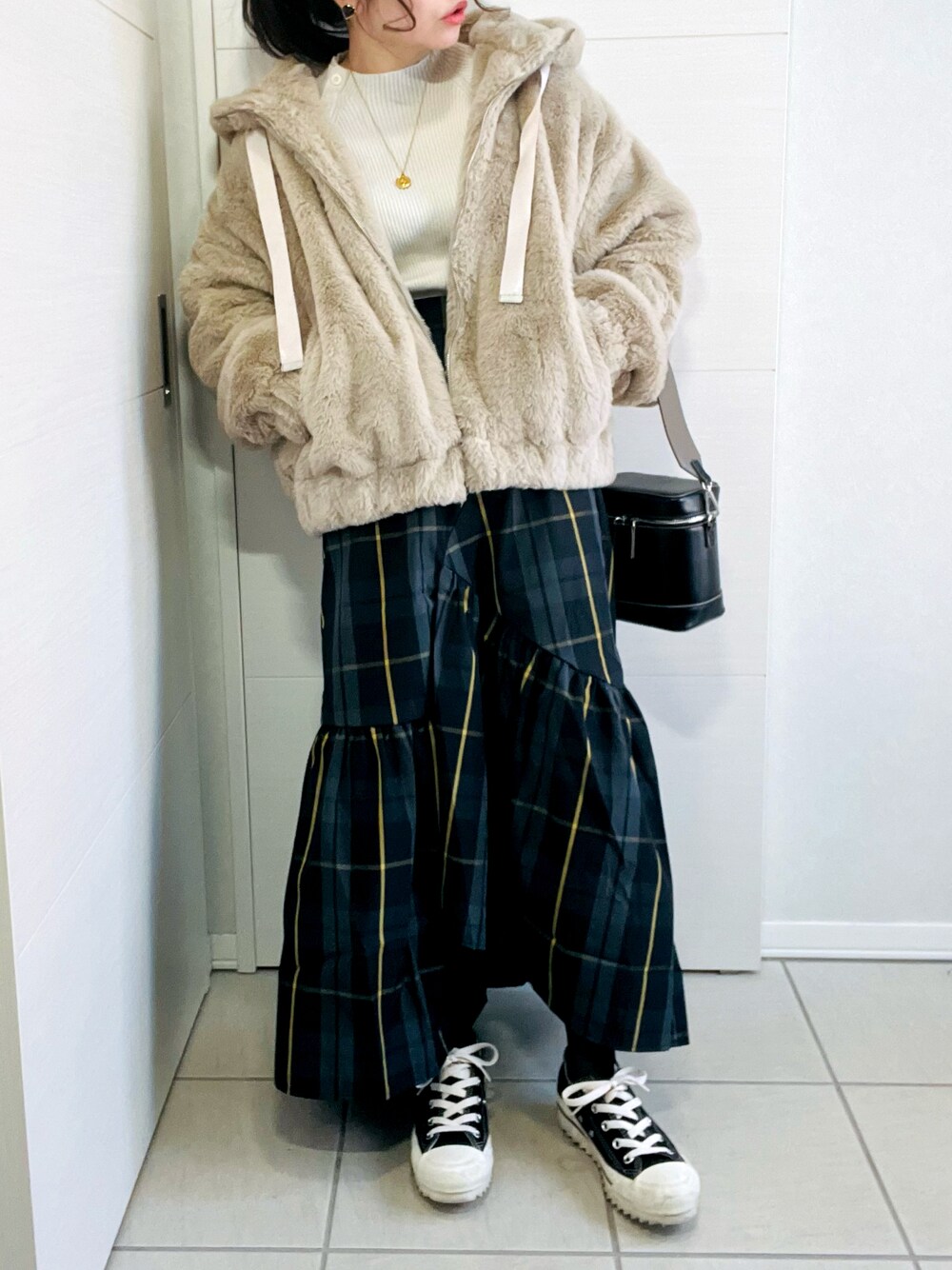 ベージュ系のブルゾン、ブラック系のスカート、ブラック系のスニーカーを着用したレディースの冬コーディネートの1枚目の写真