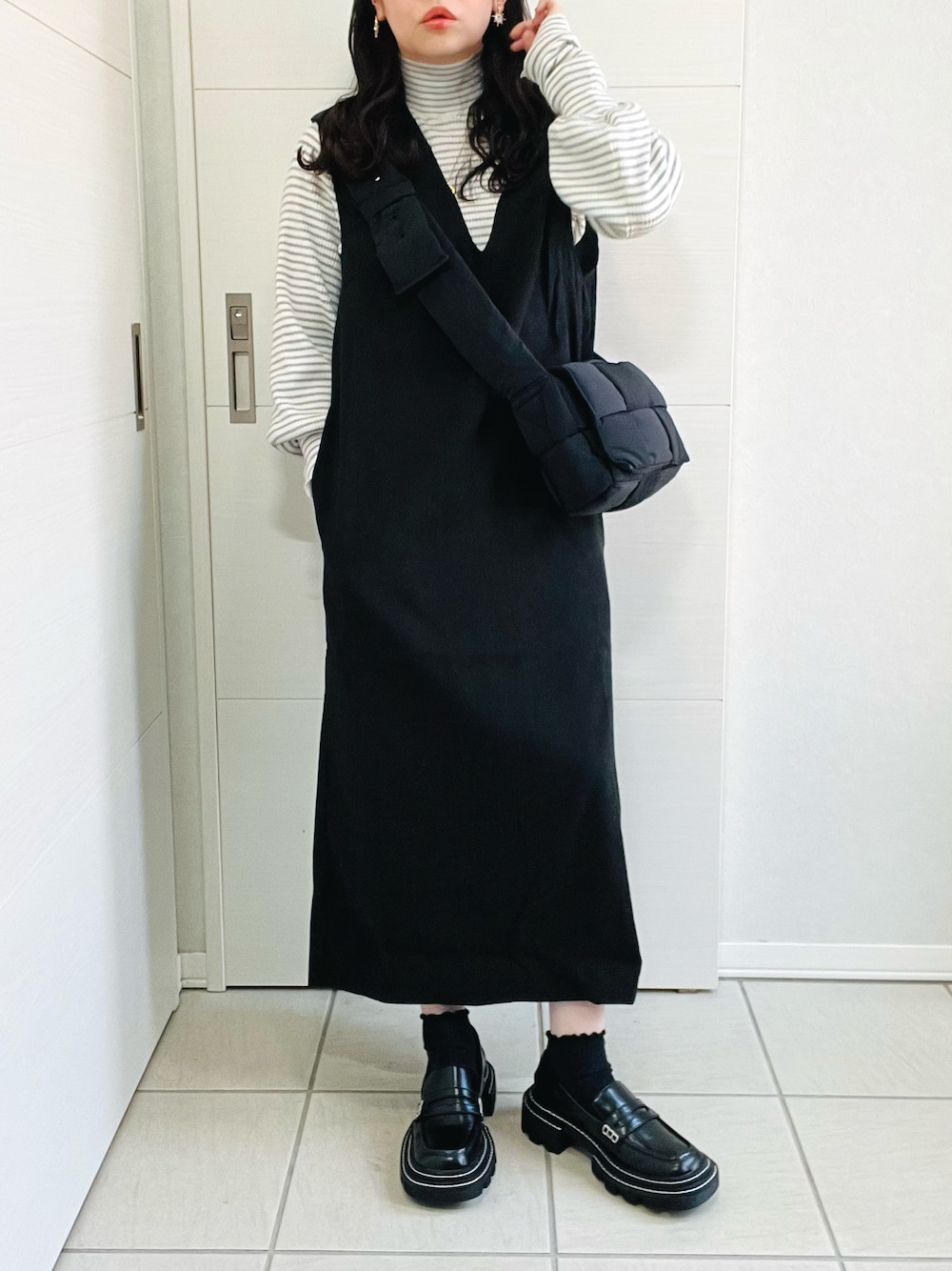 ブラック系のジャンパースカート、グレー系のニット/セーター、ブラック系のローファーを着用したレディースの秋コーディネートの1枚目の写真