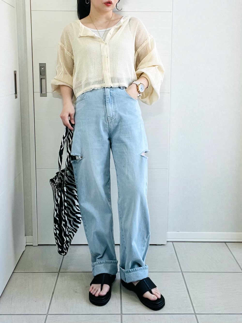 ホワイト系のカーディガン/ボレロ、ブルー系のデニムパンツ、ブラック系のサンダルを着用したレディースの春コーディネートの1枚目の写真