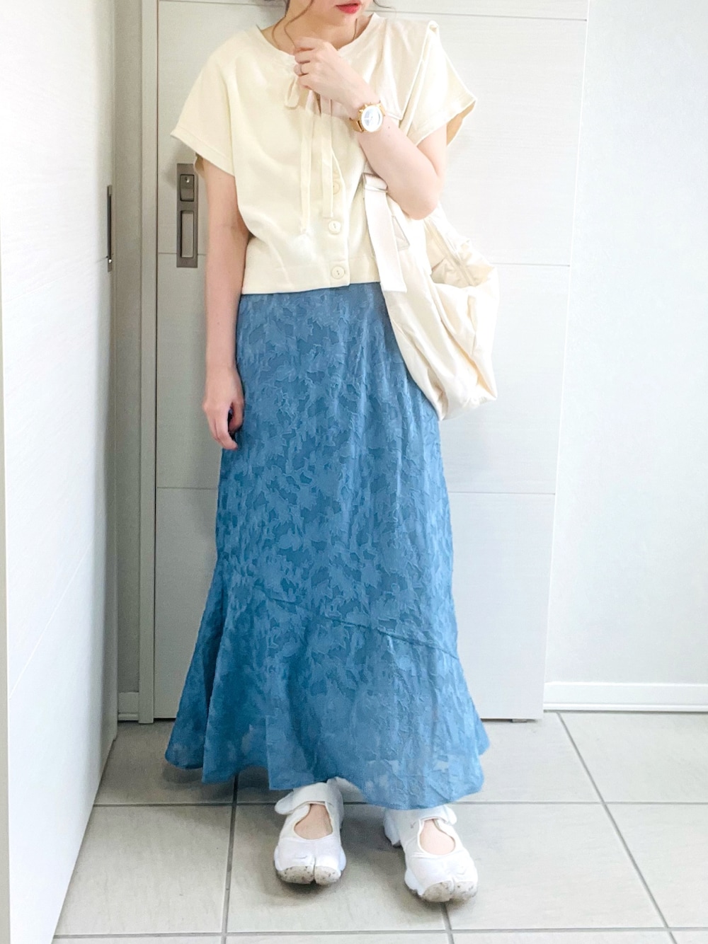 ホワイト系のカーディガン/ボレロ、ブルー系のスカート、ホワイト系のサンダルを着用したレディースの夏コーディネートの1枚目の写真