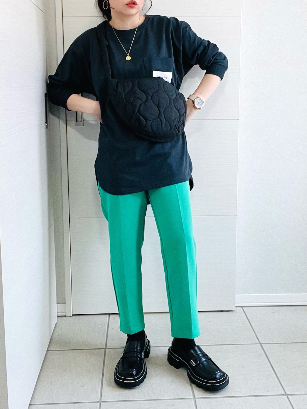 ブラック系のTシャツ/カットソー、グリーン系のスラックス、ブラック系のローファーを着用したレディースの春コーディネートの1枚目の写真