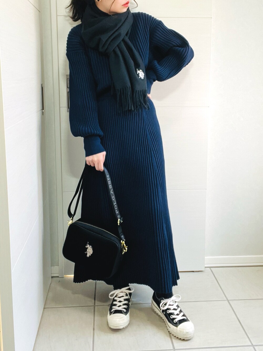 ブルー系のニット/セーター、ブルー系のスカート、ブラック系のスニーカーを着用したレディースの秋コーディネートの1枚目の写真