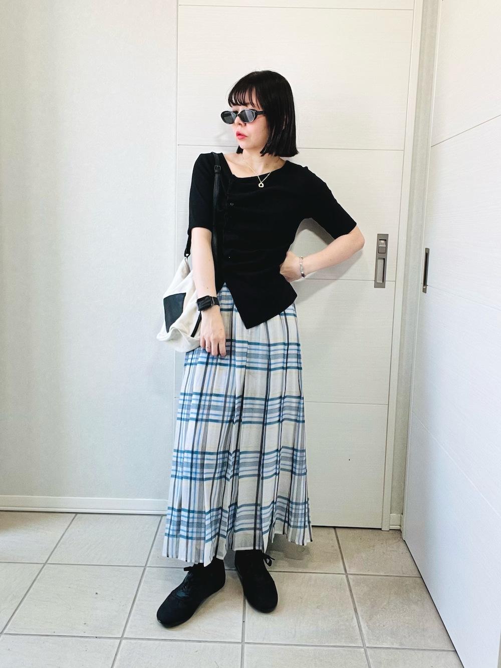 ブラック系のTシャツ/カットソー、ホワイト系のスカート、ブラック系のスニーカーを着用したレディースの秋コーディネートの1枚目の写真