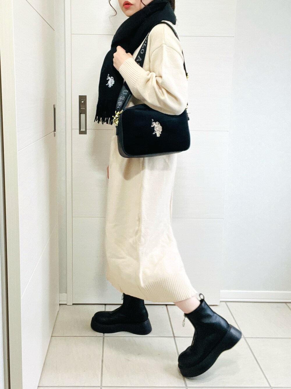 ブラック系のショルダーバッグ、ブラック系のブーツ、ホワイト系のワンピースを着用したレディースの秋コーディネートの1枚目の写真