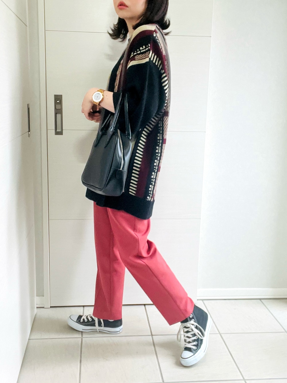 レッド系のニット/セーター、レッド系のスラックス、ブラック系のスニーカーを着用したレディースの夏コーディネートの1枚目の写真