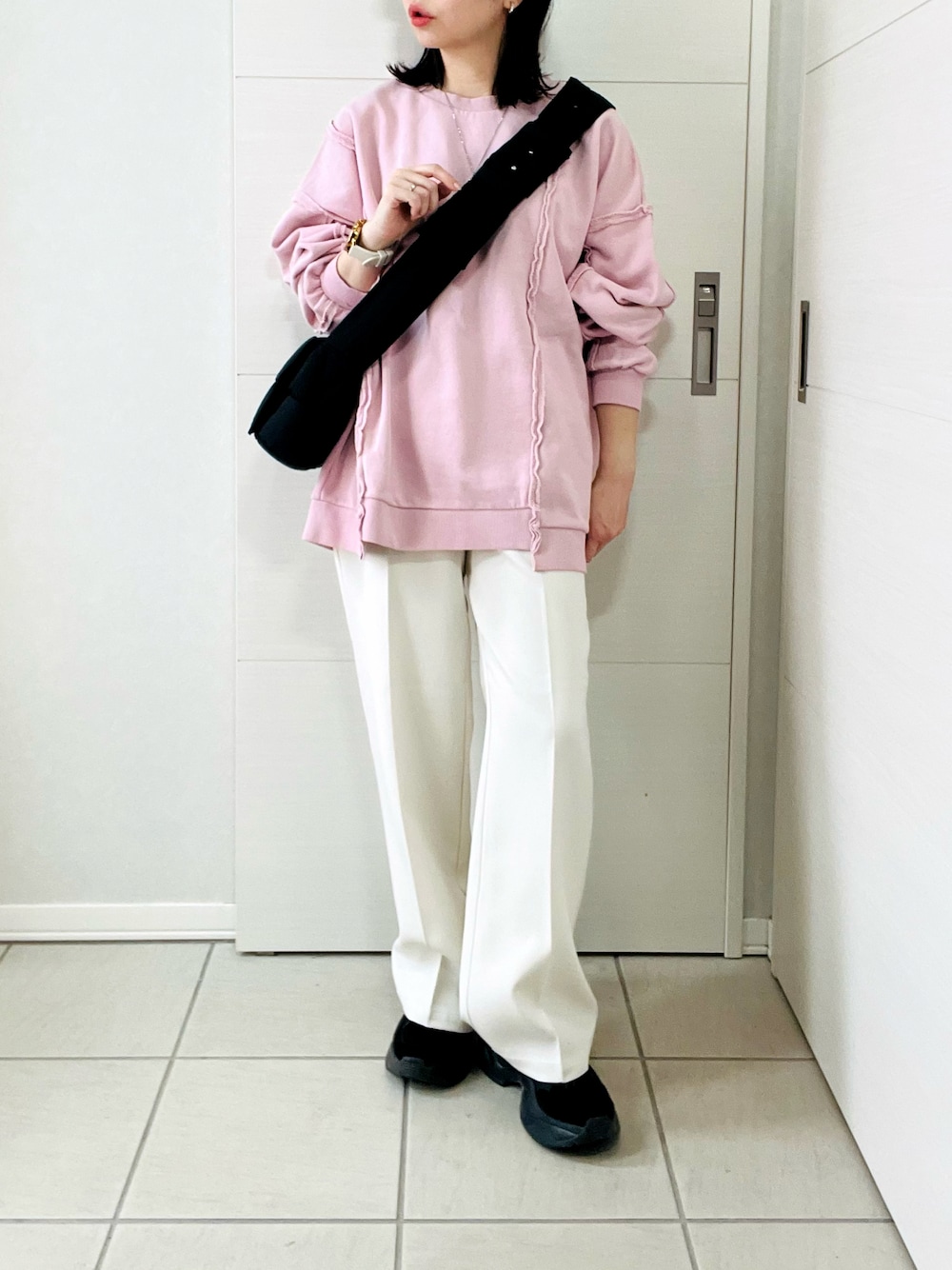ピンク系のスウェット、ホワイト系のスラックス、ブラック系のスニーカーを着用したレディースの冬コーディネートの1枚目の写真